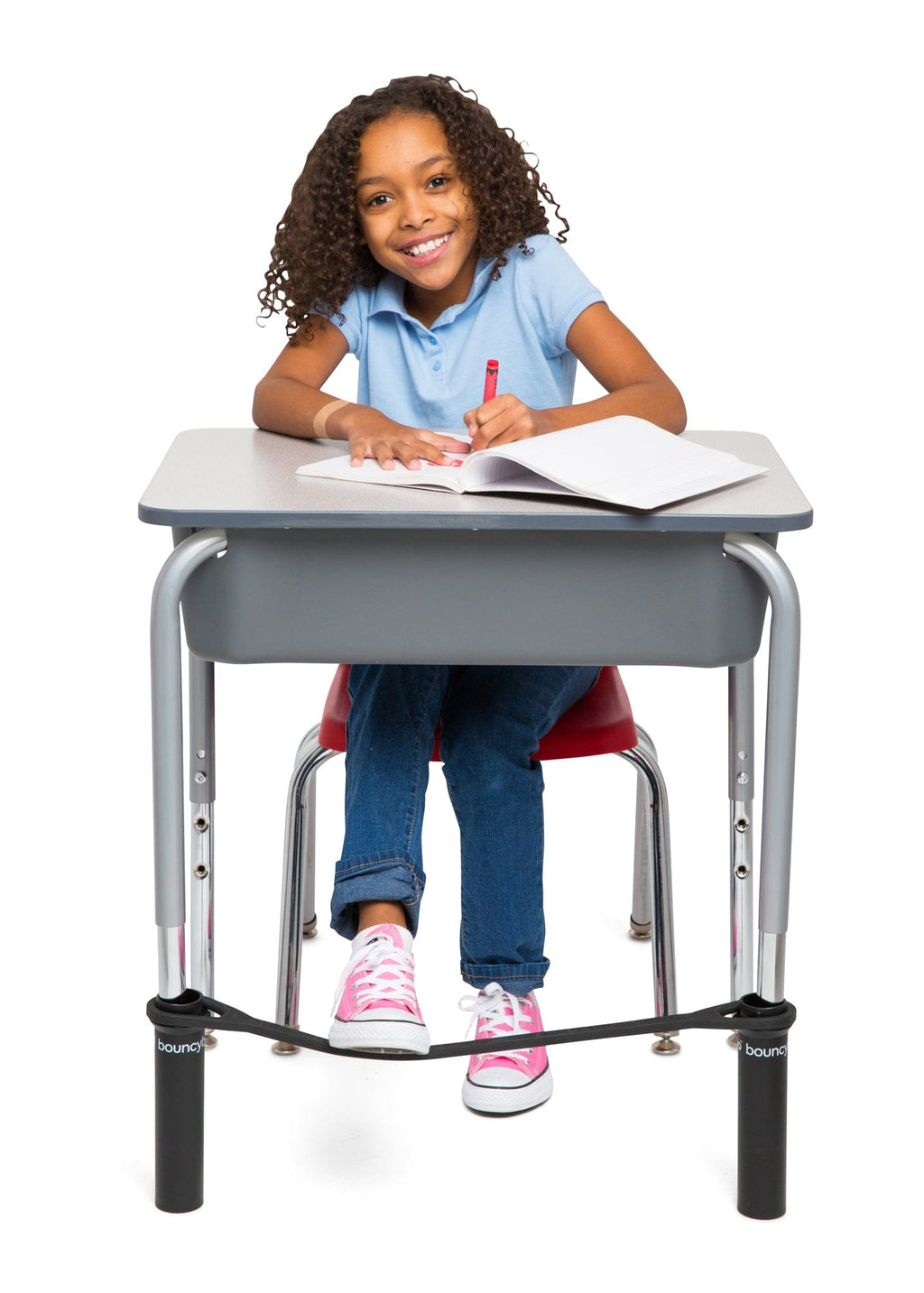 A Young Girl Writing in her Notebook While Sitting at a Desk with a Black Bouncyband.